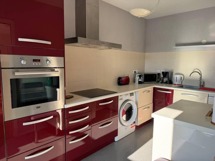 a kitchen with red cabinets and a washing machine at Appartement T3 bord de la Vienne in Chinon