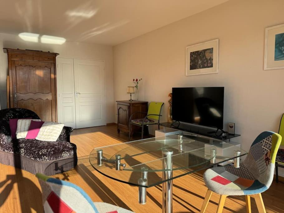a living room with a glass table and a tv at Appartement T3 bord de la Vienne in Chinon