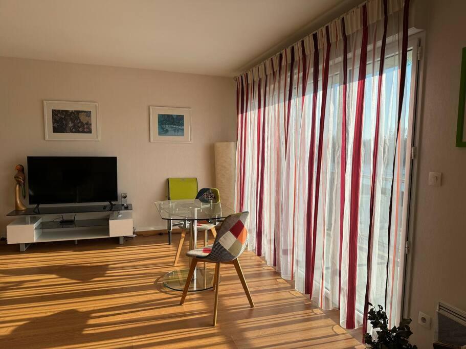 a living room with a table and a large window at Appartement T3 bord de la Vienne in Chinon