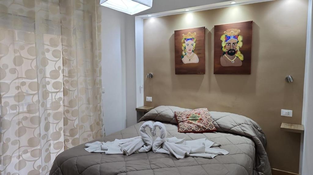 a bed in a bedroom with paintings on the wall at Milazzo La Porta Delle Eolie 2.0 in Milazzo