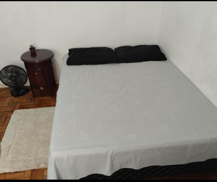 a white bed with a black pillow on top of it at Aphostel gatinhos perça caiçara in Santos