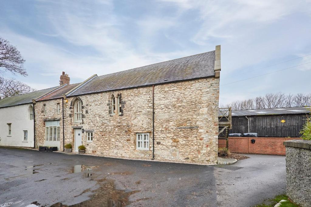 an old brick building in a parking lot at Host & Stay - Tithe Barn Cottages in Easington