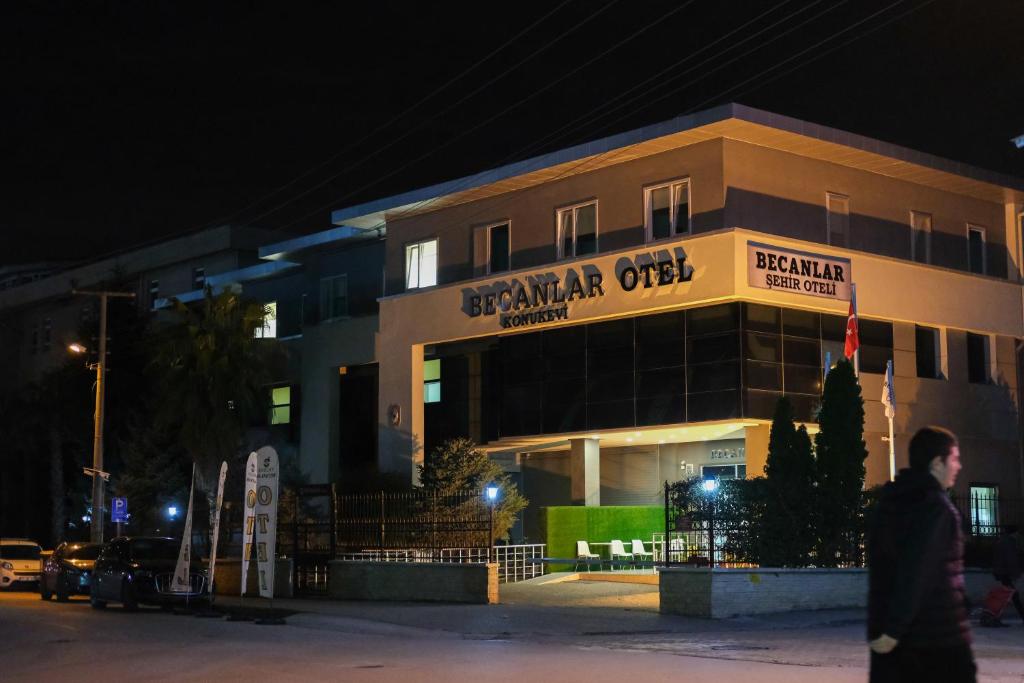 a man walking in front of a building at night at BECANLAR OTEL in Yalova