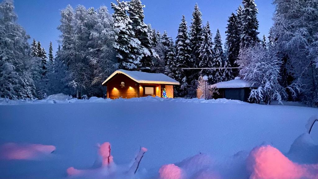 una cabina nella neve di notte con la neve di Lapin Paradise a Rovaniemi