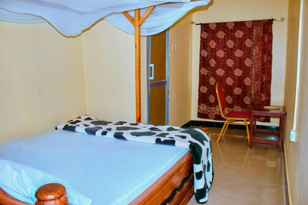 1 dormitorio con 1 cama con dosel blanco y negro en CAJANUS RESORT KARATU, en Karatu