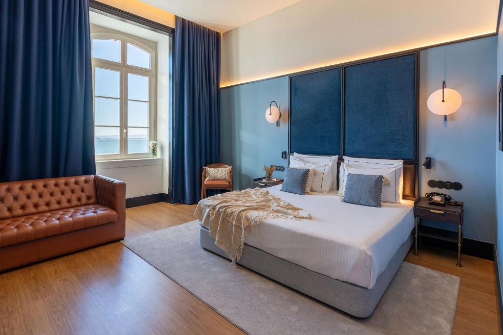 A spacious-looking bedroom with a large bed, leather sofa and waterfront window.