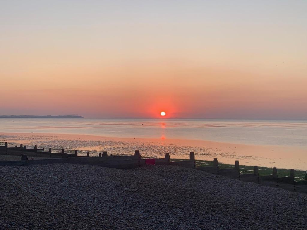 um pôr do sol na praia com o pôr do sol em Coastal home em Kent