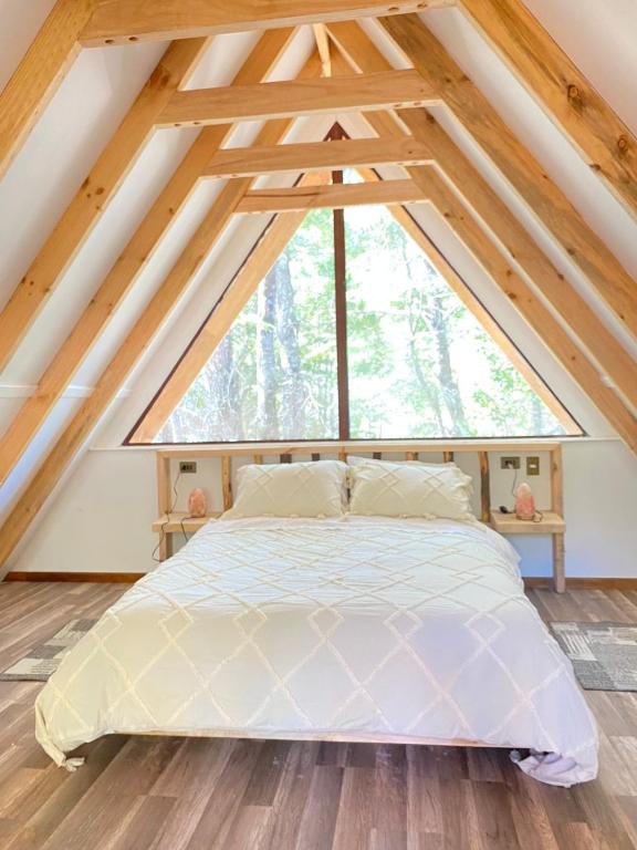 a bed in a room with a large window at Cabañas Ladera Sur in Melipeuco