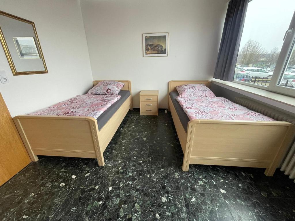 two beds in a room with two windows at Zimmer Vermietung in Pattensen