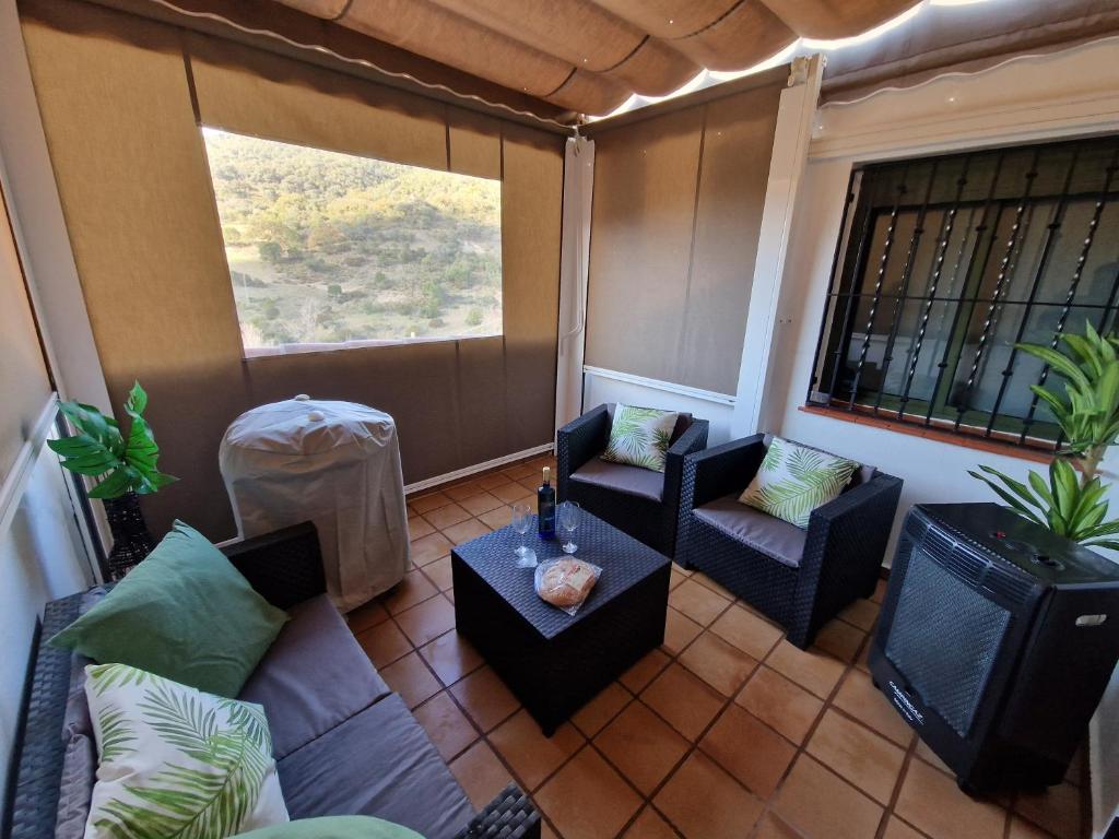 a screened in porch with two chairs and a table at Aptm Dayma Sierra junto al río Majaceite. in Benamahoma
