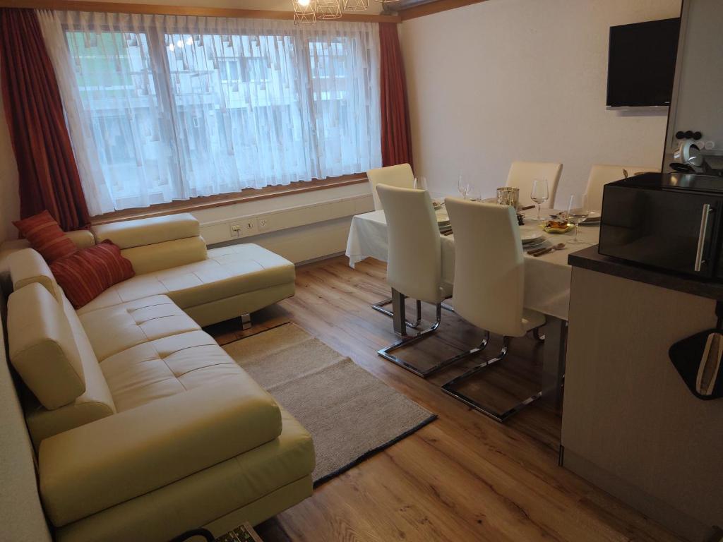 ein Wohnzimmer mit einem Sofa und einem Tisch mit Stühlen in der Unterkunft Klein aber fein in Escholzmatt