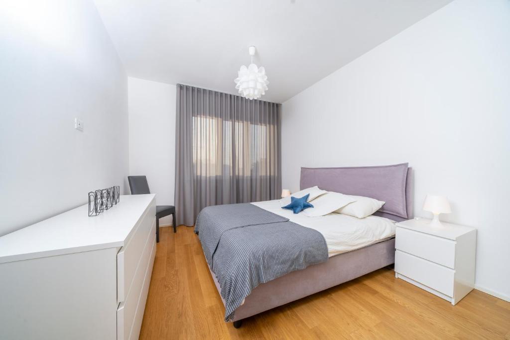 a white bedroom with a bed and a dresser at Cozy & Bright Apartment - w/ Balcony in Udine