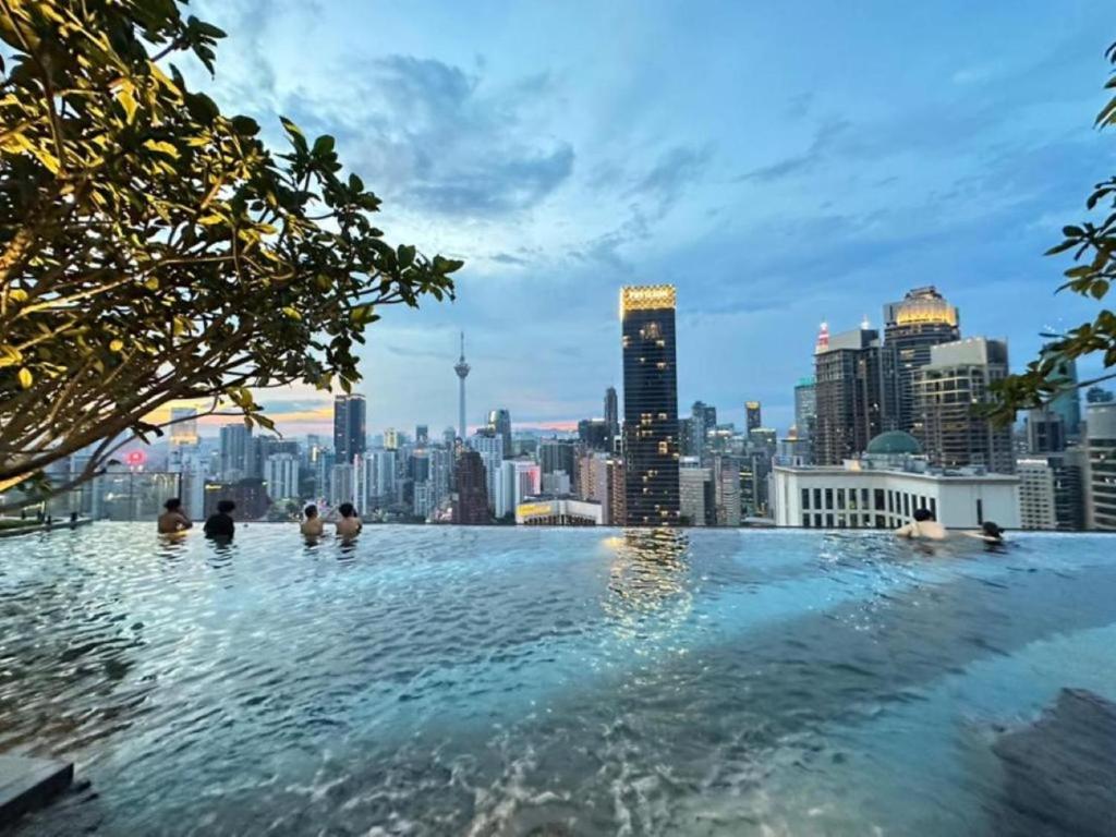 a infinity pool with a city skyline in the background at Axon Bukit Bintang By moonlight in Kuala Lumpur