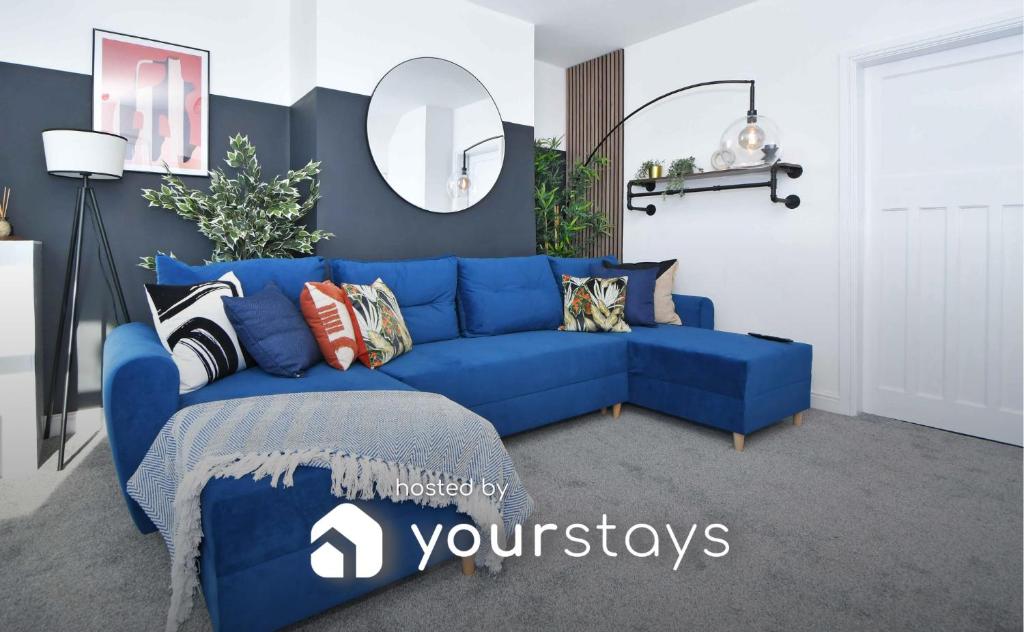 un sofá azul con almohadas en la sala de estar en Lily House by YourStays en Crewe