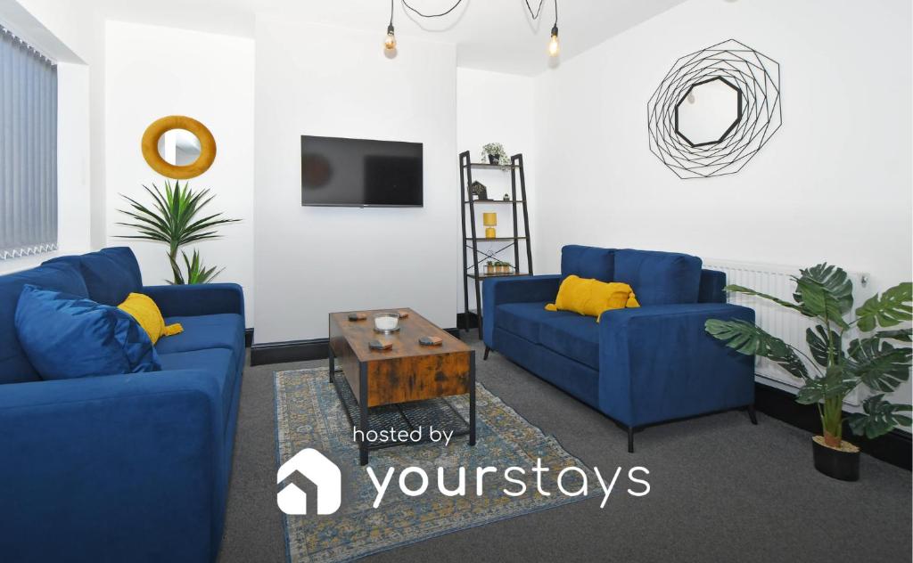 ein Wohnzimmer mit 2 blauen Sofas und einem Tisch in der Unterkunft Potter's Rest by YourStays in Stoke on Trent