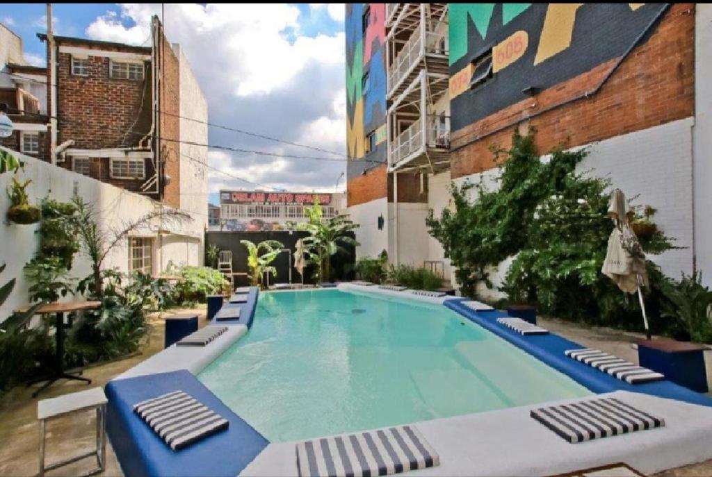 a large swimming pool with lounge chairs and a building at House of Cairo - Johannesburg in Johannesburg