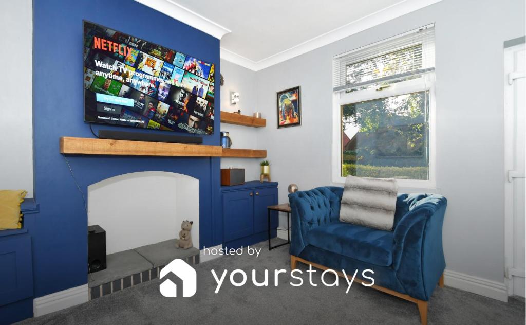 uma sala de estar com uma cadeira azul e uma televisão em Squirrel Cottage by YourStays em Stoke on Trent