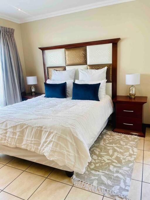 ein Schlafzimmer mit einem großen Bett mit blauen Kissen in der Unterkunft A Warm 3 bed Townhouse in a secure complex in Witbank