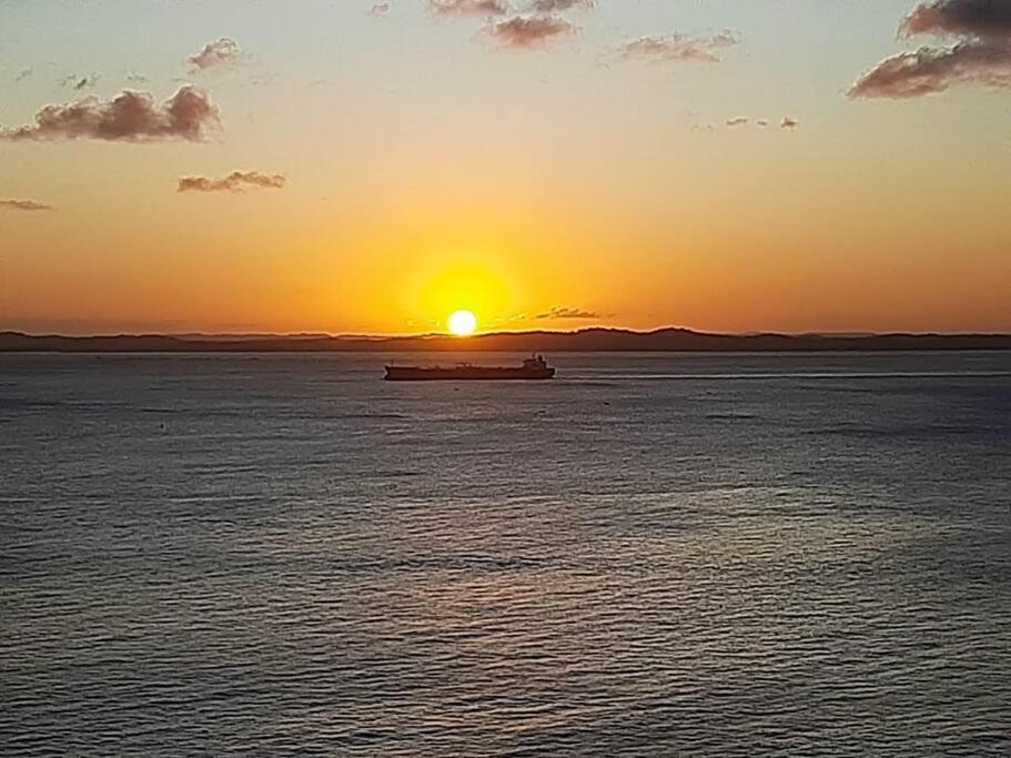 um barco no oceano com o pôr do sol ao fundo em Flat no Sol Vitória Marina 2 em Salvador