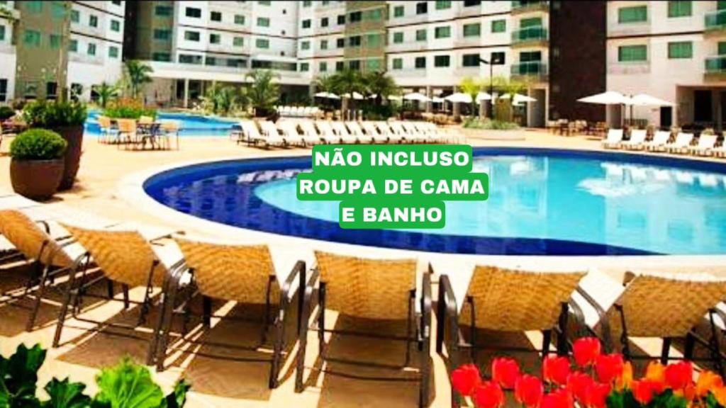 a swimming pool with chairs and a sign in front of a building at Caldas Novas Riviera in Caldas Novas