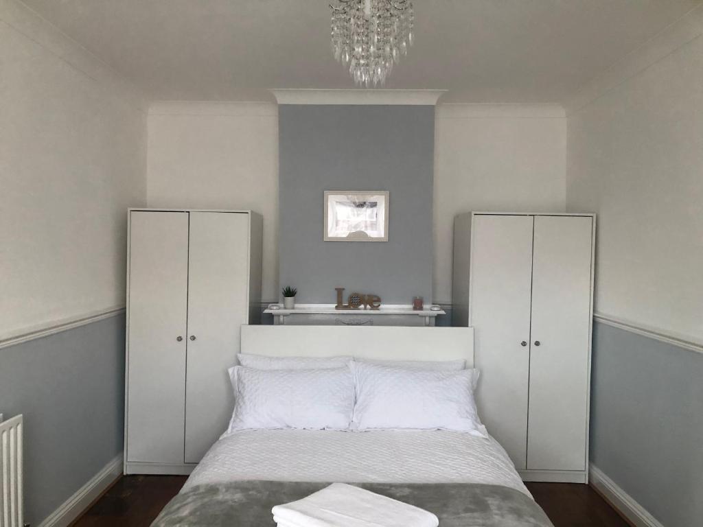 a bedroom with a bed with white cabinets and a chandelier at Butterfly Home in London