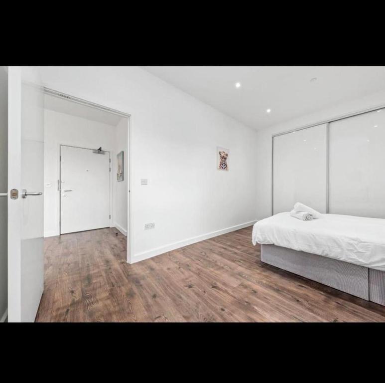 a white bedroom with a bed and a mirror at Delta 1 Br Apartment in London DP328 in Croydon