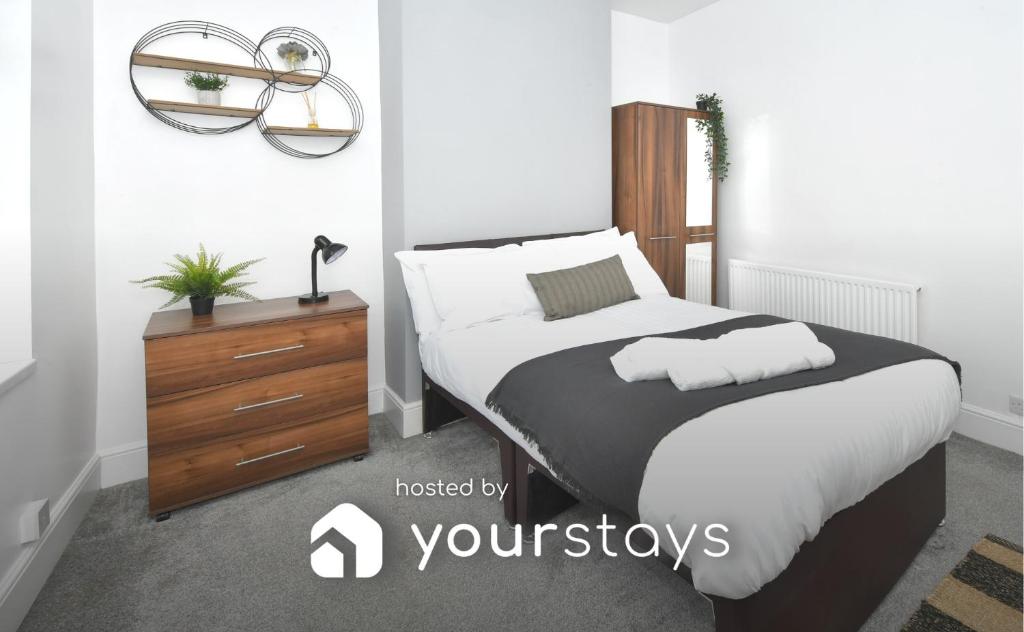 a bedroom with a large bed and a wooden dresser at Boothen House by YourStays in Stoke on Trent