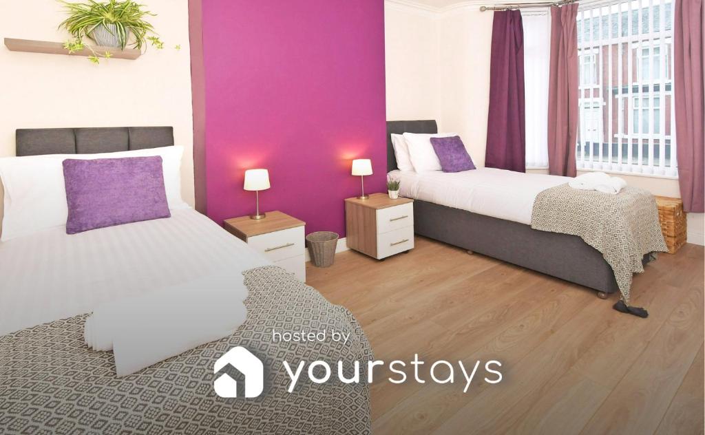 two beds in a room with purple walls and wooden floors at Book Somerville House - Stylish Family Home from Home in Crewe