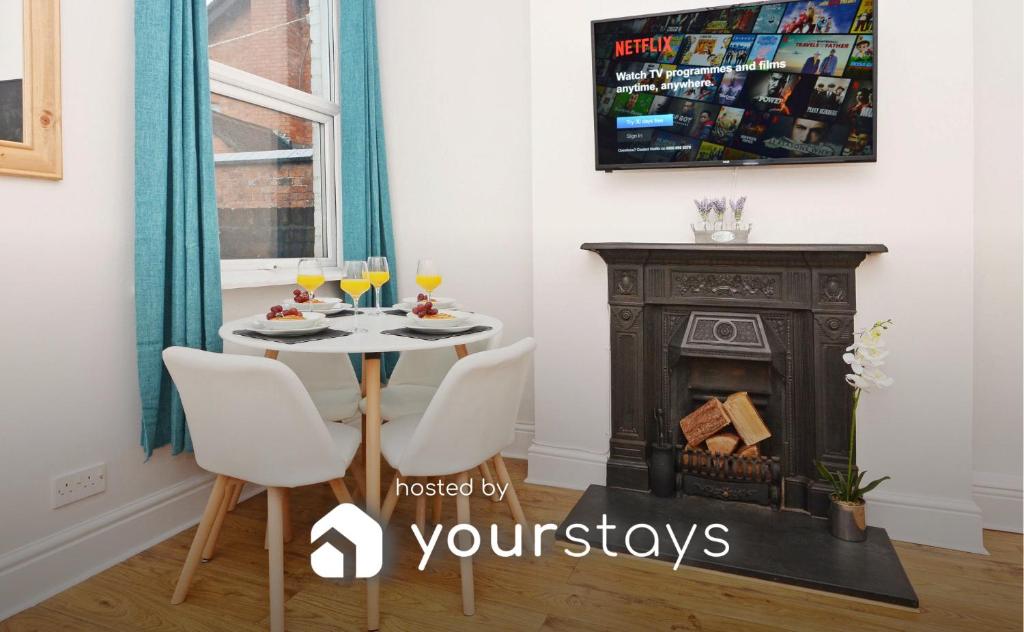 a dining room with a table and a fireplace at Venture House by YourStays in Stoke on Trent