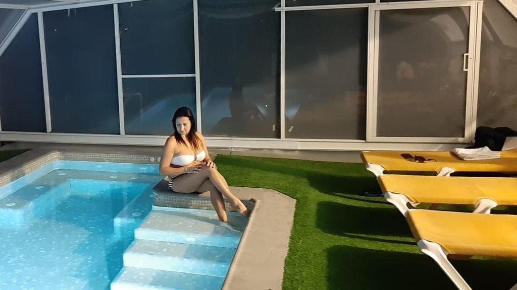 una donna seduta accanto alla piscina di Villa con piscina privada climatizada 29ºC a Santa Susanna