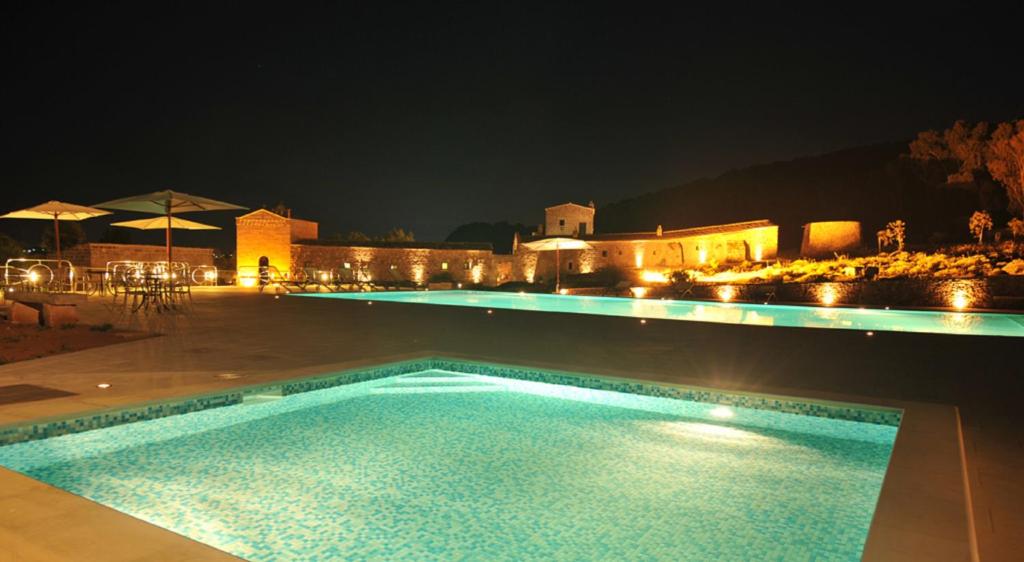 a swimming pool at night with a building in the background at Masseria Pizzofalcone in Supersano