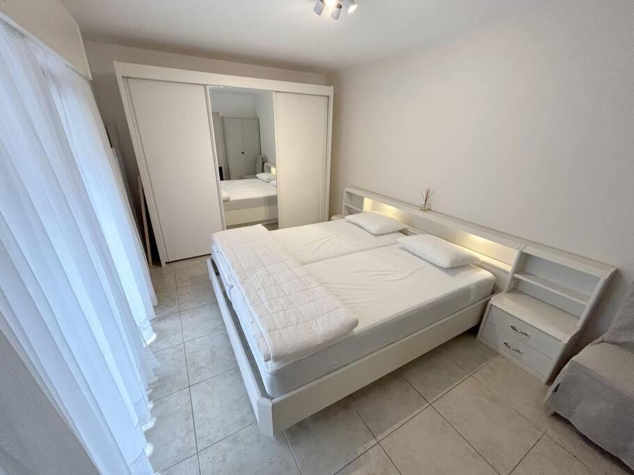 a white bedroom with a bed and a mirror at Appartement met 2 slaapkamers-VAYA G002 in De Panne