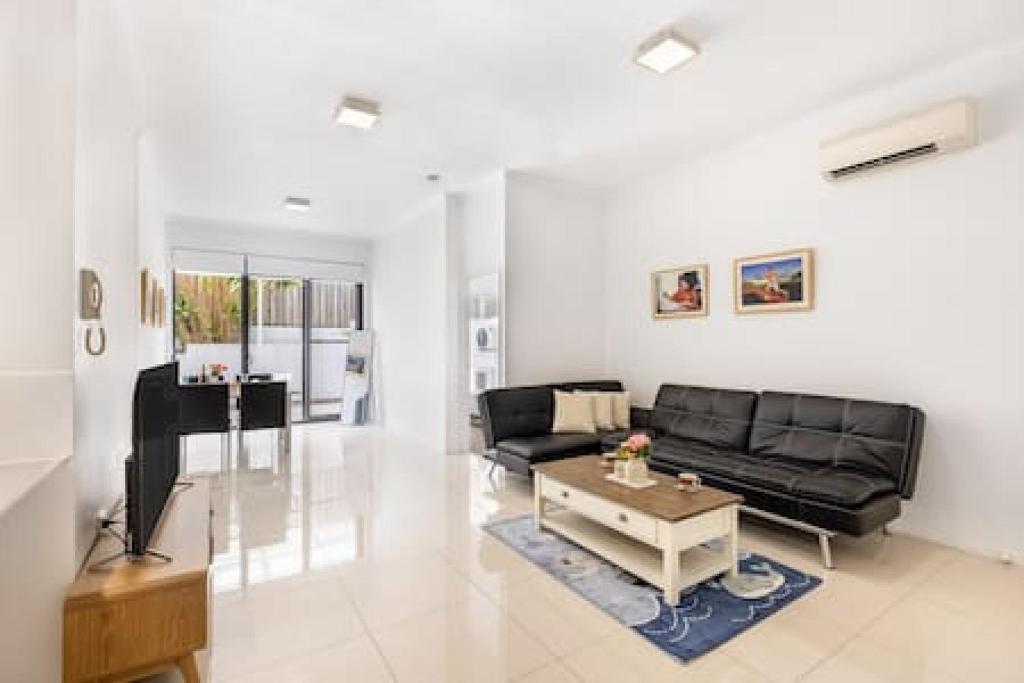 a living room with a black couch and a table at Central of Toowong Neat Apt Near Station in Brisbane