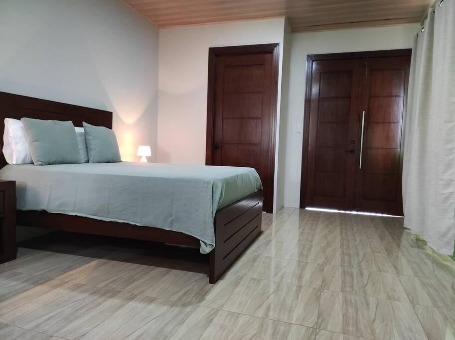 a bedroom with a bed and two wooden doors at Mandy Loft -40MB wifi -estacionamiento gratuito in San Ramón