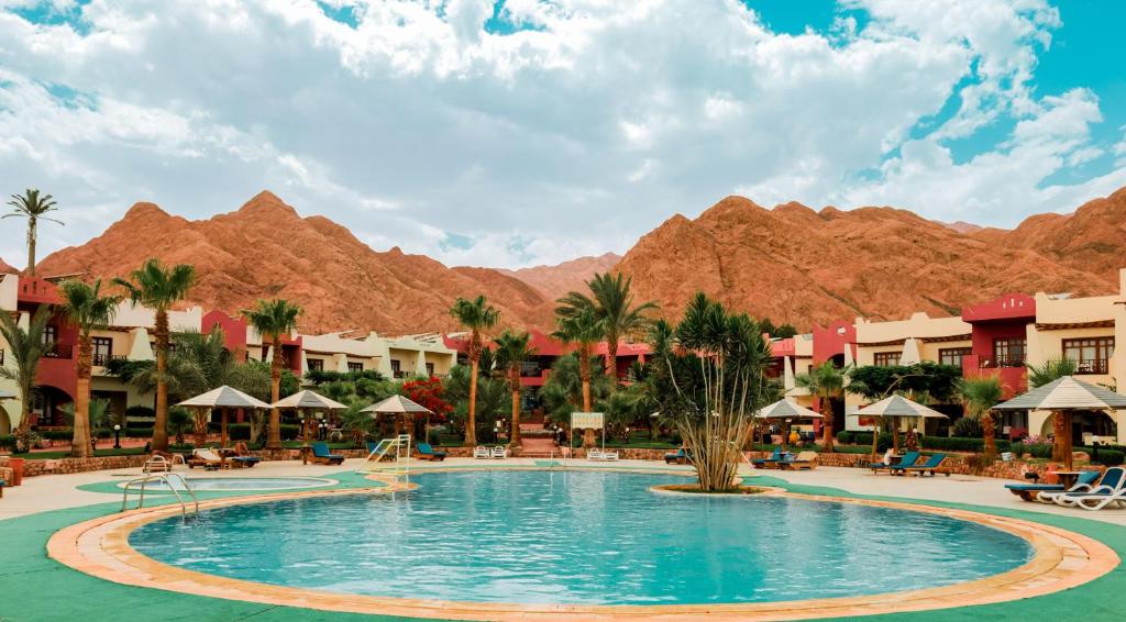 ein Pool in einem Resort mit Bergen im Hintergrund in der Unterkunft Tropitel Dahab Oasis in Dahab