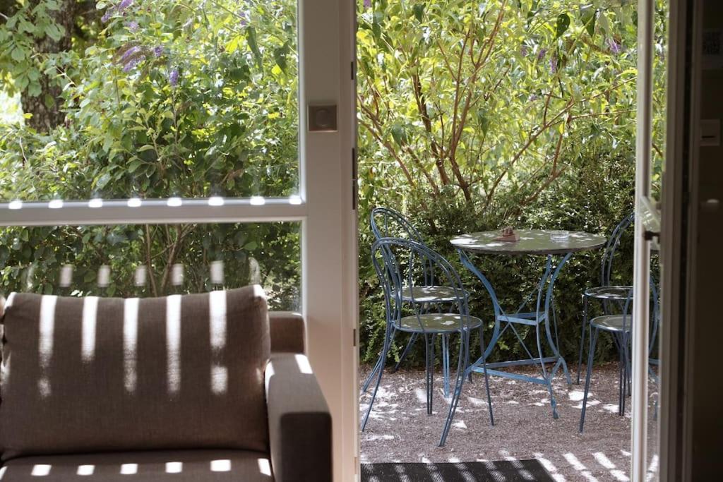 una puerta abierta a un patio con mesa y sillas en Appartement avec terrasse en pleine nature, en Ougney-Douvot