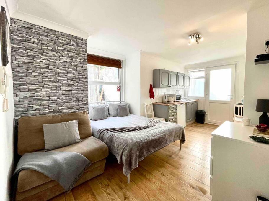 a bedroom with a bed and a brick wall at A beautiful studio flat with garden in London