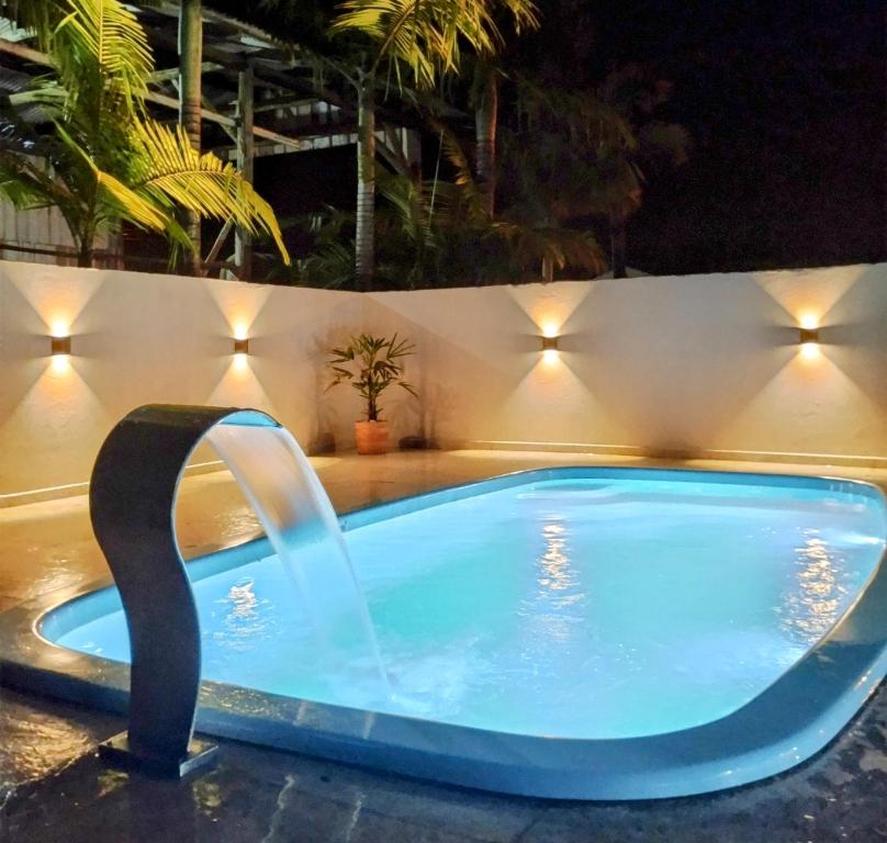 una piscina por la noche con una fuente de agua en Férias Perfeitas, Praia e Piscina en Itapoa
