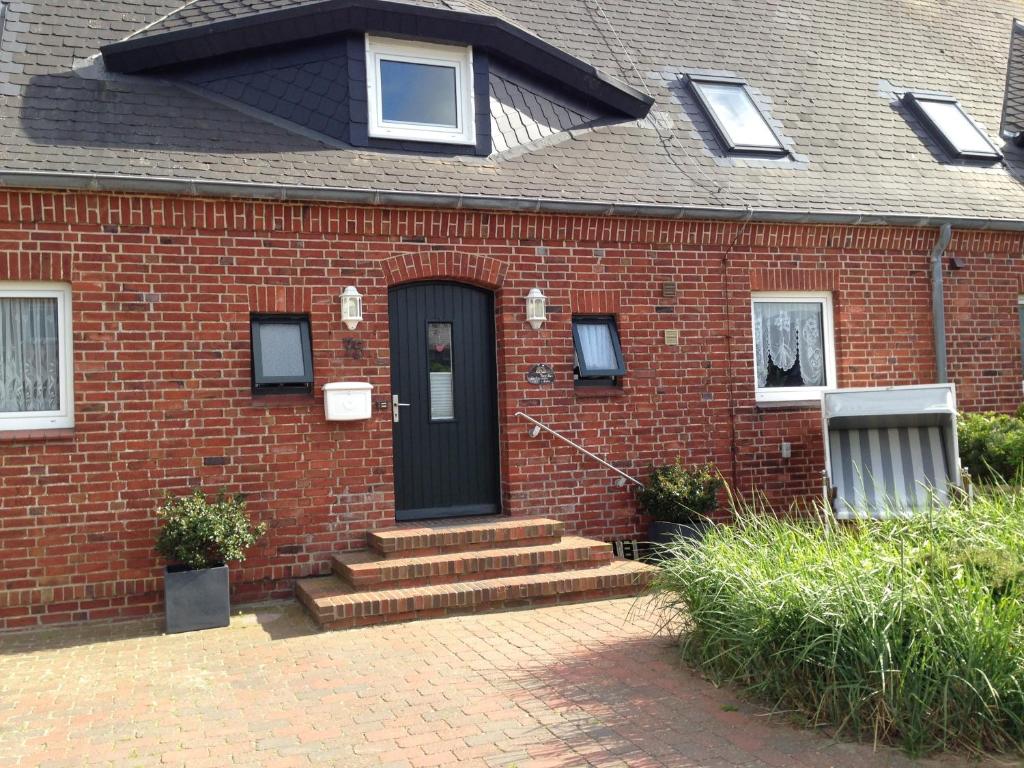 a brick house with a black door and stairs at Lichtis Hues in List