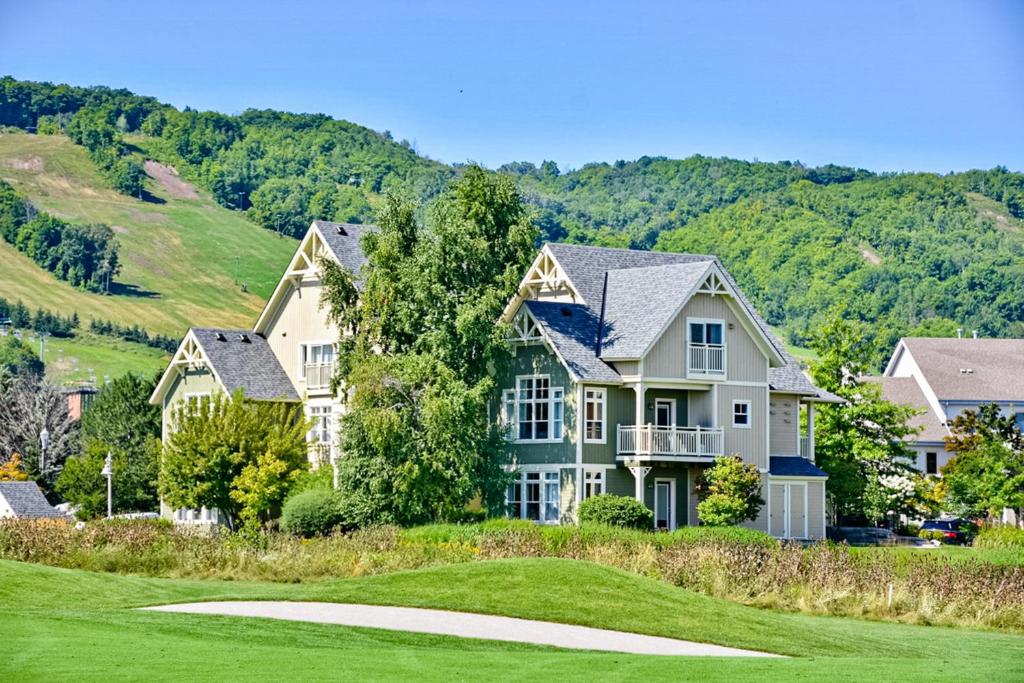 una casa en un campo de golf con montañas en el fondo en Rivergrass, en Blue Mountains