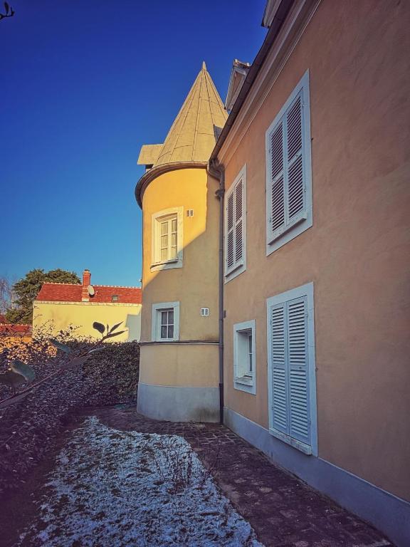un bâtiment avec une tour sur son côté dans l'établissement Le jardin de l'arbre sec + parking, proche château., à Fontainebleau