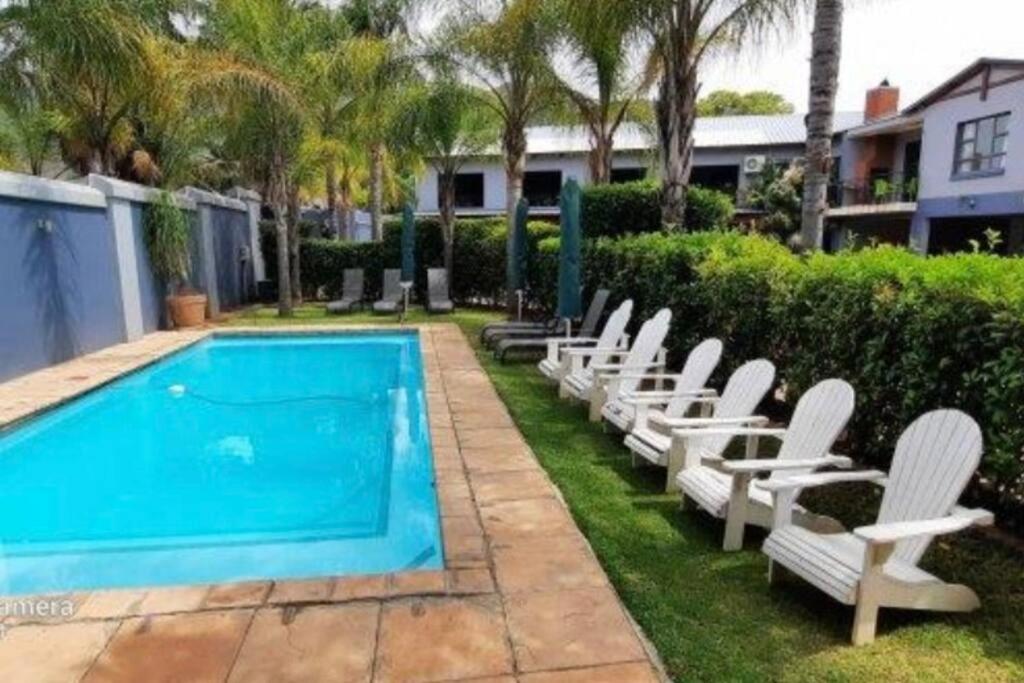 a row of white chairs next to a swimming pool at Honeymoon suite in Schoemansville in Hartbeespoort