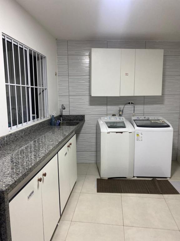 uma cozinha com armários brancos e uma máquina de lavar e secar roupa em Casa Ceci SUÍTES/QUARTOS em São Paulo
