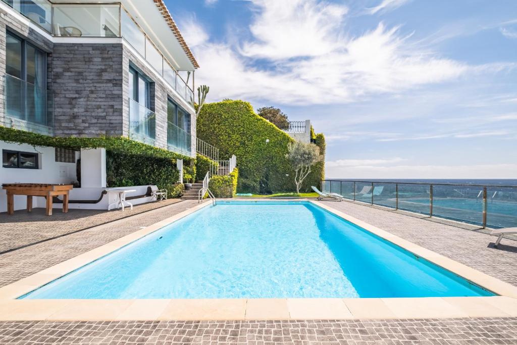 a swimming pool in front of a house with the ocean at Beach House - By WeHost in Santa Cruz
