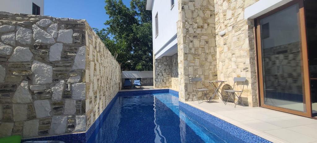 una casa con piscina junto a una pared de piedra en Olive Garden's Paradise Villa, en Skarinou