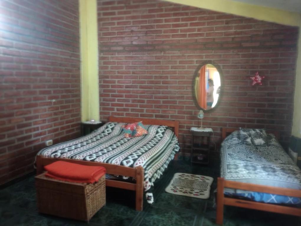 um quarto com duas camas numa parede de tijolos em Casa Colibri em Merlo