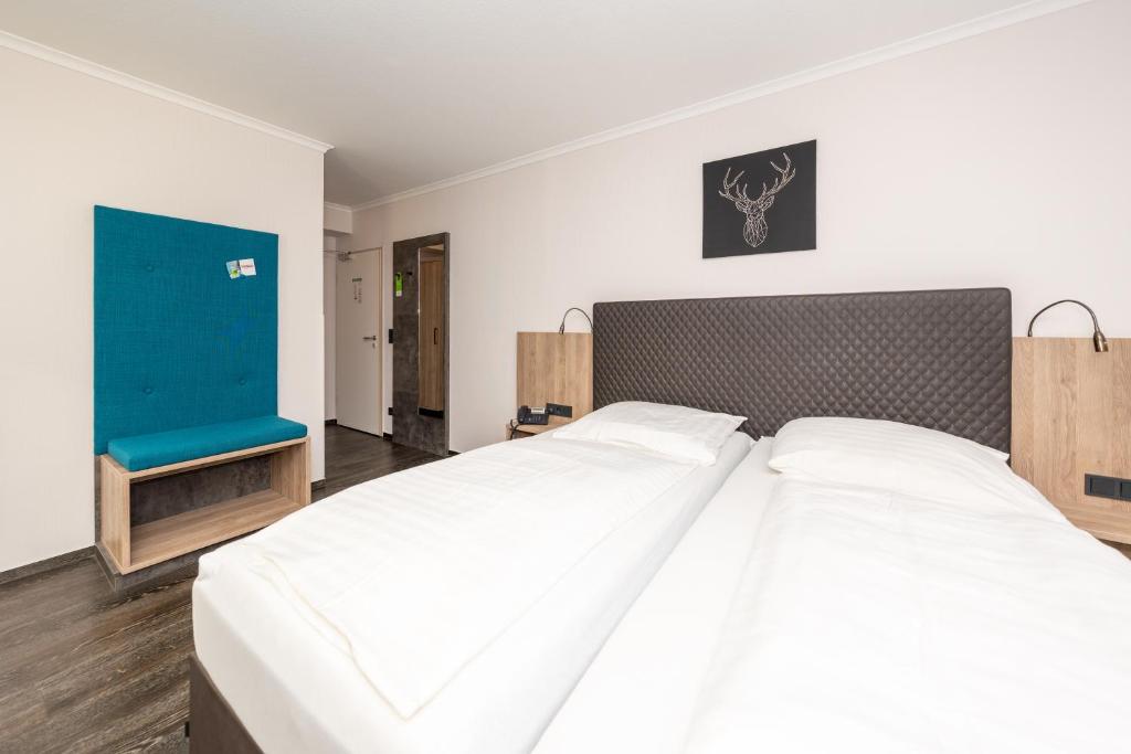 ein Schlafzimmer mit einem großen weißen Bett und einem blauen Stuhl in der Unterkunft Tespo Hotel und Sportpark in Kaarst