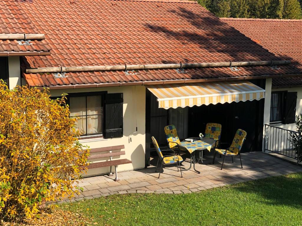 um pátio com uma mesa e cadeiras e um telhado em Lechbruck am See Feriendorf Hochbergle Haus 95 em Lechbruck