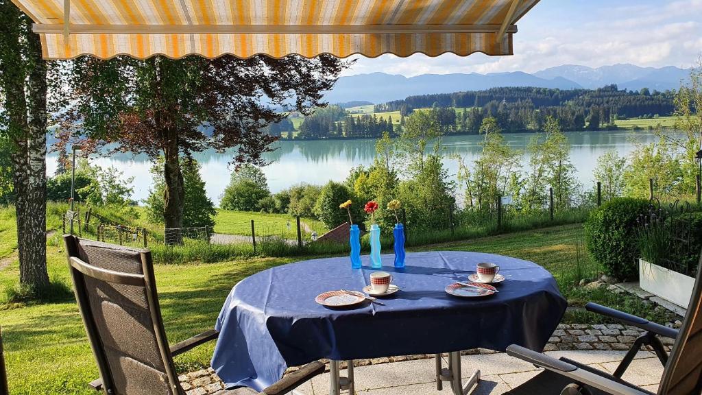 a blue table with a view of a lake at Lechbruck am See Feriendorf Hochbergle Haus 142 - Lechseeblick in Lechbruck