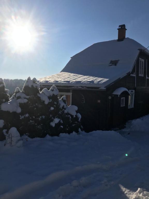 a house covered in snow with the sun behind it at Lesanka in Všelibice